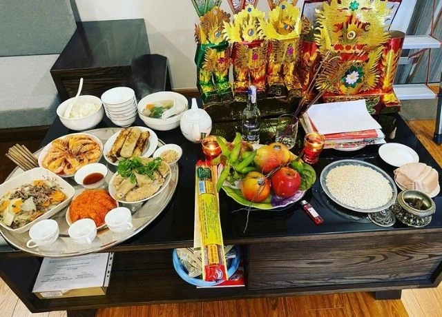 Bà lão và cháu gái đang chuẩn bị mâm cúng Ông Công Ông Táo với các lễ vật truyền thống.