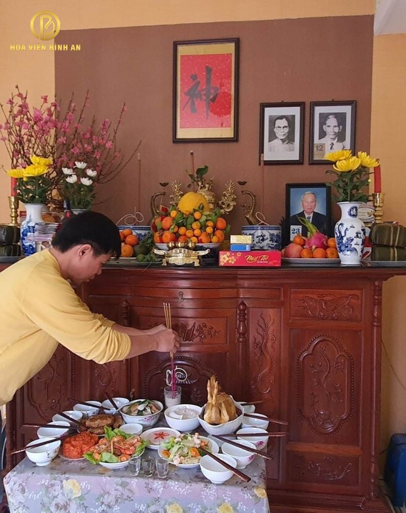 Bàn thờ gia tiên với hình ảnh tổ tiên và mâm lễ vật cúng hóa vàng