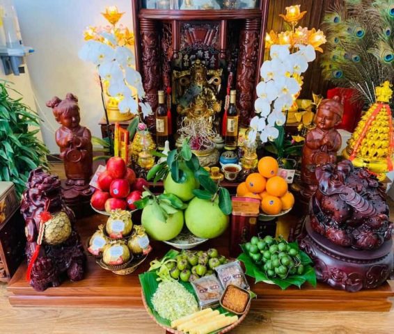Bàn thờ Thần Tài Thổ Địa được trang trí tươm tất với mâm ngũ quả, hoa tươi và các vật phẩm cúng bái cho đêm Giao thừa.
