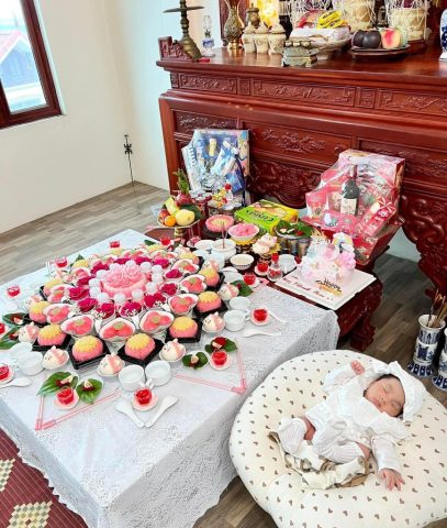 alt text: Mâm cúng đầy tháng truyền thống với xôi chè, hoa quả, nến hương bày biện trang trọng